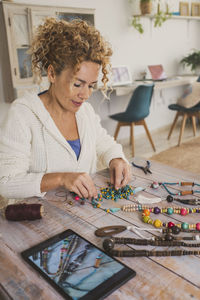 Young woman using digital tablet while sitting on table