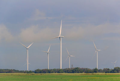 Windmills on field against sky