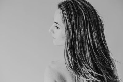 Rear view of woman with long hair looking away against wall