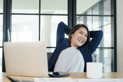 Young woman using phone while sitting on table