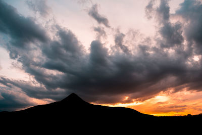 Low angle view of silhouette mountain against dramatic sky