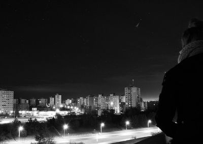 Rear view of illuminated buildings in city at night