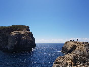 Rock formation in sea against clear blue sky