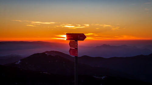 Cross sign on mountain against sky during sunset