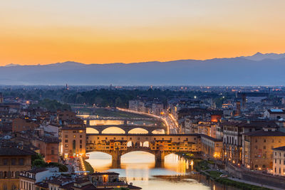 Illuminated buildings in city during sunset