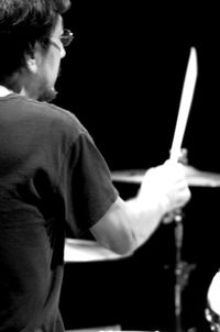 Rear view of man holding cigarette against black background