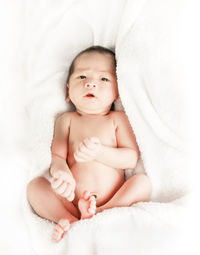 Portrait of baby girl lying on bed