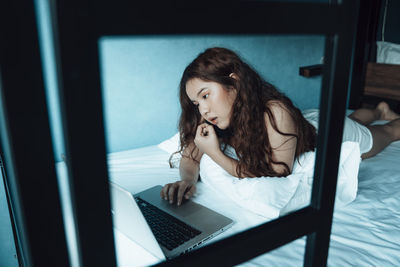 Young woman looking at camera while sitting on bed