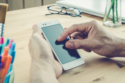 Midsection of man using mobile phone on table