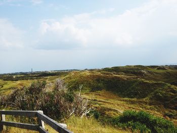 Scenic view of grassy field against cloudy sky