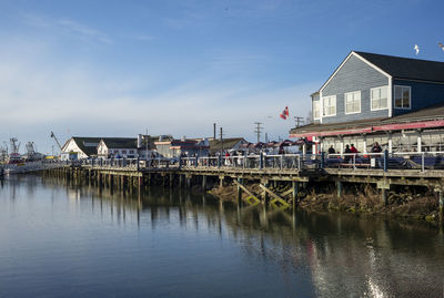 Buildings by river against sky