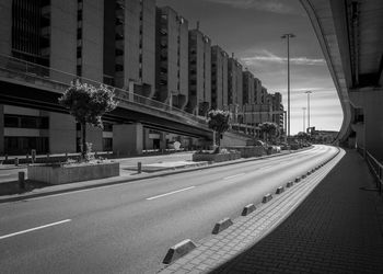 Road by buildings against sky in city