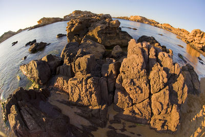 Rock formation on shore against sky