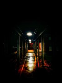 Empty corridor along illuminated building at night