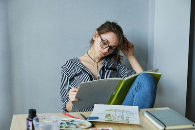 Millennial girl draws fabulous images on paper while sitting at home