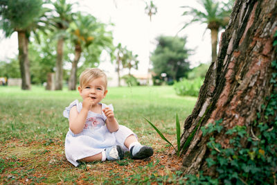 Full length of smiling girl sitting on grass at park