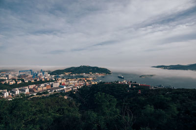 High angle view of city by sea against sky