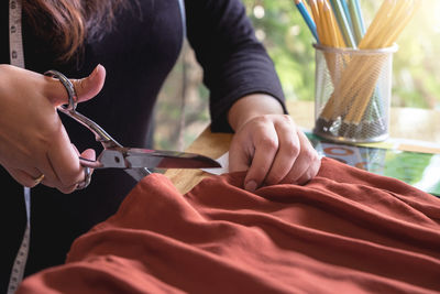 Midsection of tailor cutting textile at office