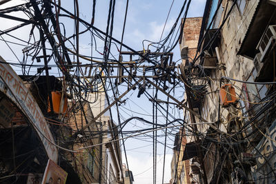 Low angle view of electricity pylon and buildings against sky