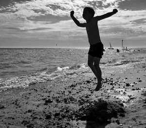 Silhouette boy jumping at beach during sunny day