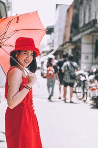 Woman with red umbrella standing in city