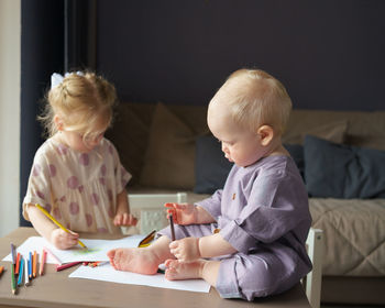 Two kids brother and sister drawing and playing together at home