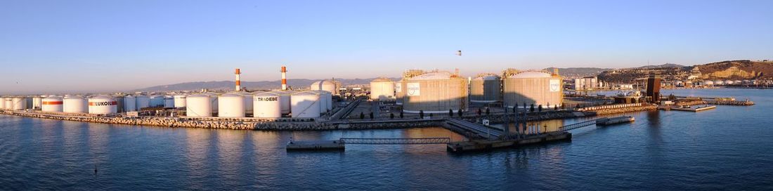 View of factory by sea against clear sky