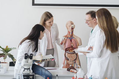 Professor with students analyzing anatomy model in class