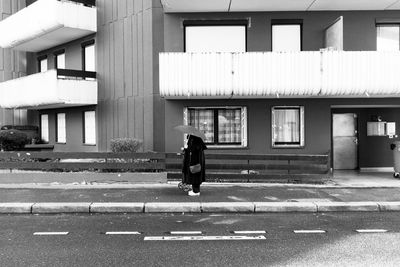 Full length of woman walking on street against building