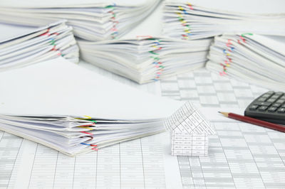 High angle view of model house with pencil and calculator on financial documents