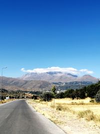 Road amidst landscape against blue sky