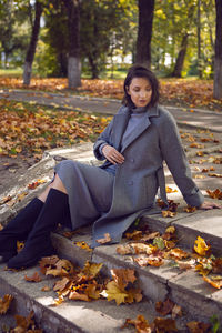 Young woman sitting on tree trunk