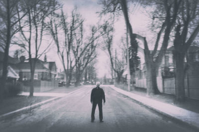 Rear view of man walking on snow covered road