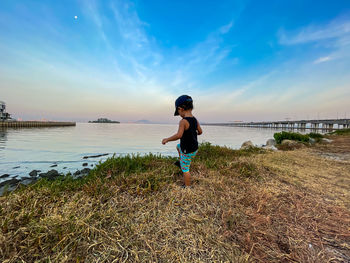 Little boy standing on beach against sky