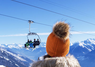 Rear view of woman on snowcapped mountain against sky