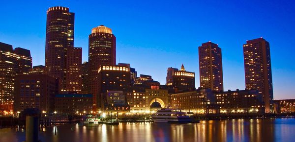 Illuminated buildings by city against sky at night