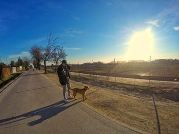 Rear view of woman with dog walking on road