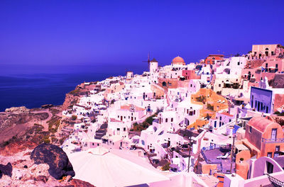 High angle view of townscape by sea against blue sky