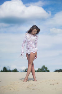 Full length of woman standing on beach against sky