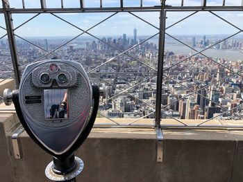 Close-up of coin-operated binoculars against cityscape and sky