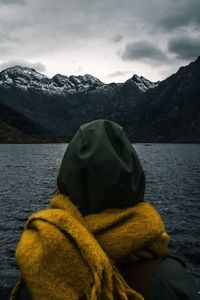 Rear view of woman looking at lake by mountain against sky