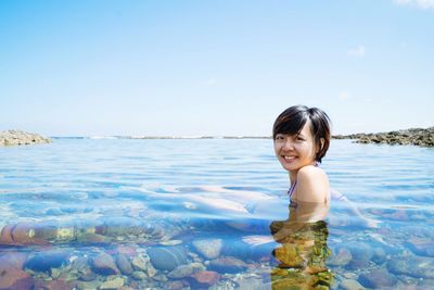 Portrait of happy mid adult woman in sea against sky