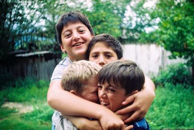 Close-up of smiling friends embracing at back yard