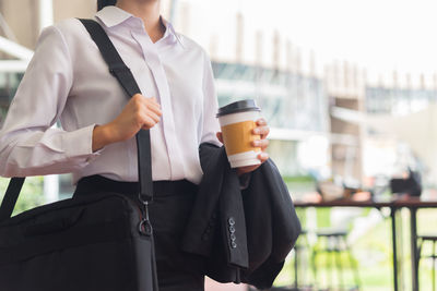 Midsection of businesswoman holding disposable cup