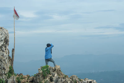 Man photographing mountains against sky