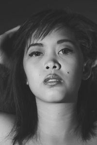 Close-up portrait of young woman with lipstick against black background