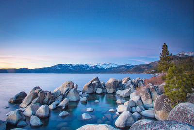 Rocks by sea against blue sky