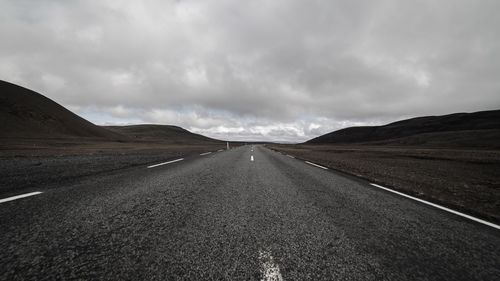 Road passing through landscape against cloudy sky