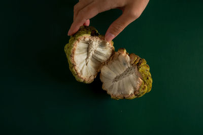 Close-up of hand holding ice cream against black background