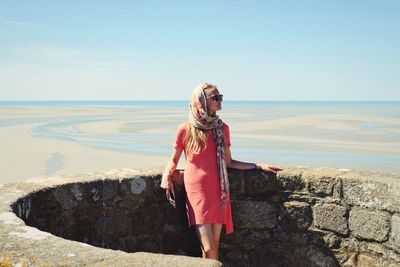 Woman standing at beach against sky